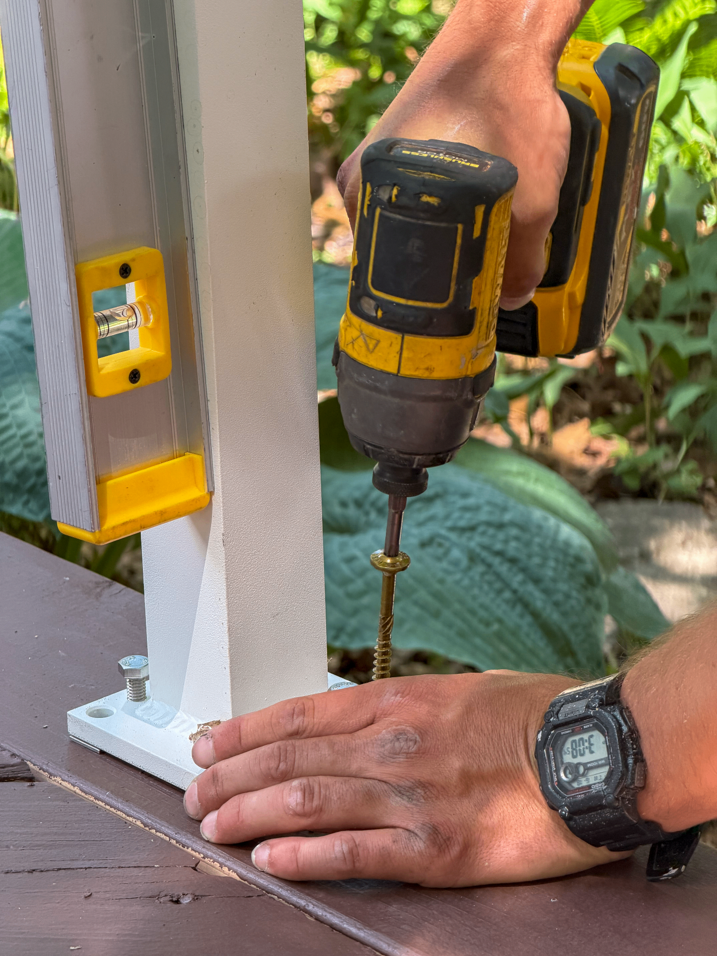 Crew installing a deck post with a drill and level