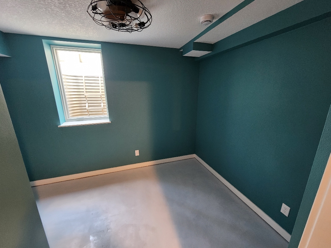 Finished basement room repainted in teal with new baseboard after water damage rebuild